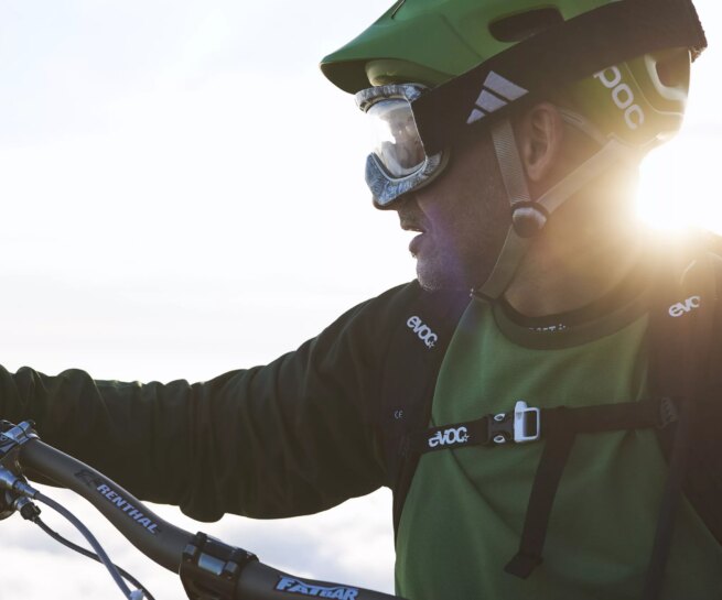 Sport & lifestyle - immagine di un biker MTB con maglia e casco verde con raggio di sole dietro la nuca