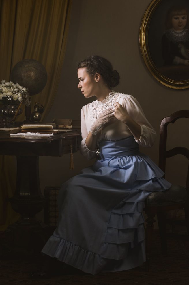 portrait od young woman in Victorian age clothing reading letter.