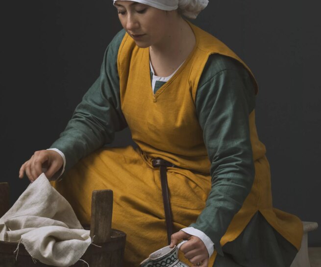 Historic portrait of a young woman in medieval clothing doing laundry. Personal project dedicated to historic portraits. Image series by David Umberto Zappa - portrait, commercial and advertising photographer. Studio photography. Set-design. Ritratto storico di giovane donna in abiti medievali intenta a lavare i panni.. Progetto personale del fotografo commerciale, pubblicitario, ritrattista ed editoriale David Umberto Zappa. Fotografia in studio. Set-design.