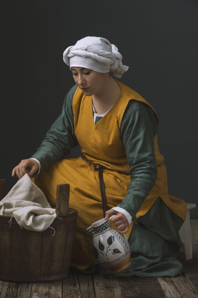 Historic portrait of a young woman in medieval clothing doing laundry. Personal project dedicated to historic portraits. Image series by David Umberto Zappa - portrait, commercial and advertising photographer. Studio photography. Set-design. Ritratto storico di giovane donna in abiti medievali intenta a lavare i panni.. Progetto personale del fotografo commerciale, pubblicitario, ritrattista ed editoriale David Umberto Zappa. Fotografia in studio. Set-design.