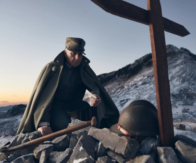 Portrait of Alberto Simonelli wearing a World War I Italian Infantry Man Uniform. Image shot on Monte Sagro, Tuscany, Italy showing Alberto looking a a cross and army helmet surrounded by swan during sunset.Personal project dedicated to historic portraits. Image series by David Umberto Zappa - portrait, commercial and advertising photographer. Ritratto di Alberto Simonelli, in uniforme militare Mitragliere Italiano Prima Guerra Mondiale. Immagine scattata sul Monte Sagro, Toscana. Alberto chino su una croce ed elmetto circondato da neve sotto le luci del tramonto. Progetto personale del fotografo commerciale, pubblicitario, ritrattista ed editoriale David Umberto Zappa.