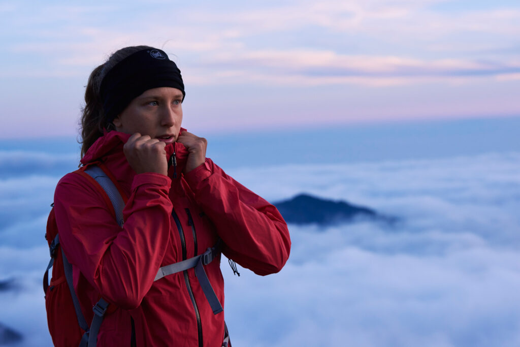 Ritratto di ragazza al tramonto realizzato in quota, presso Campocecina Massa Carrara. Nuvole sullo sfondo. Ragazza tiene la giacca sportiva. Realizzato per Polygiene da duzimage di David Umberto Zappa, fotografo in Provincia di La Spezia