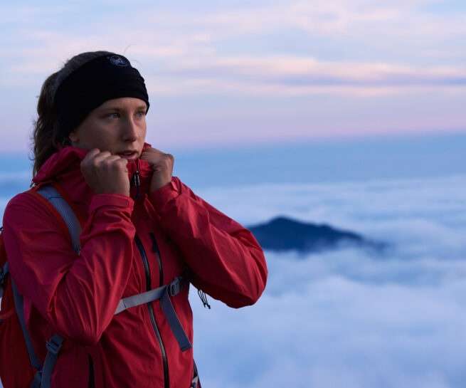 Ritratto di ragazza al tramonto realizzato in quota, presso Campocecina Massa Carrara. Nuvole sullo sfondo. Ragazza tiene la giacca sportiva. Realizzato per Polygiene da duzimage di David Umberto Zappa, fotografo in Provincia di La Spezia