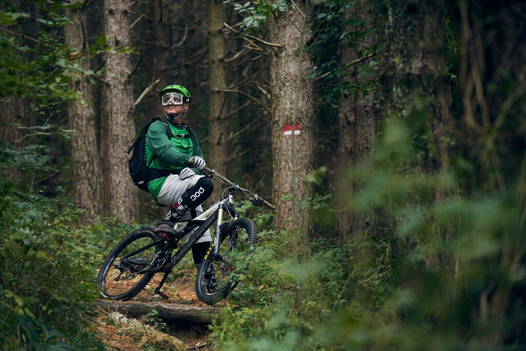 Immagine di biker bicicletta nel bosco mentre si guarda attorno vestito con attrezzatura POC. Immagine sportiva creata per Polygiene dal fotografo duzimage - David Umberto Zappa in provincia di La Spezia