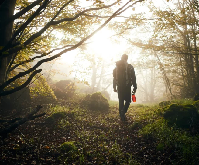 Portfolio Sport & Lifestyle del fotografo duzimage. Profilo di uomo in controluce nel bosco con zaino, borraccia, nebbia, luce suggestiva.