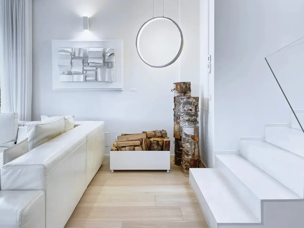 Interior design, immagine di un salotto con divano e scale monocromatico bianco. Elementi in legno: tronco e parquet. Immagine realizzata dal fotografo immobiliare duzimage La Spezia per agenzia immobiliare TheDreamRe Forte dei Marmi