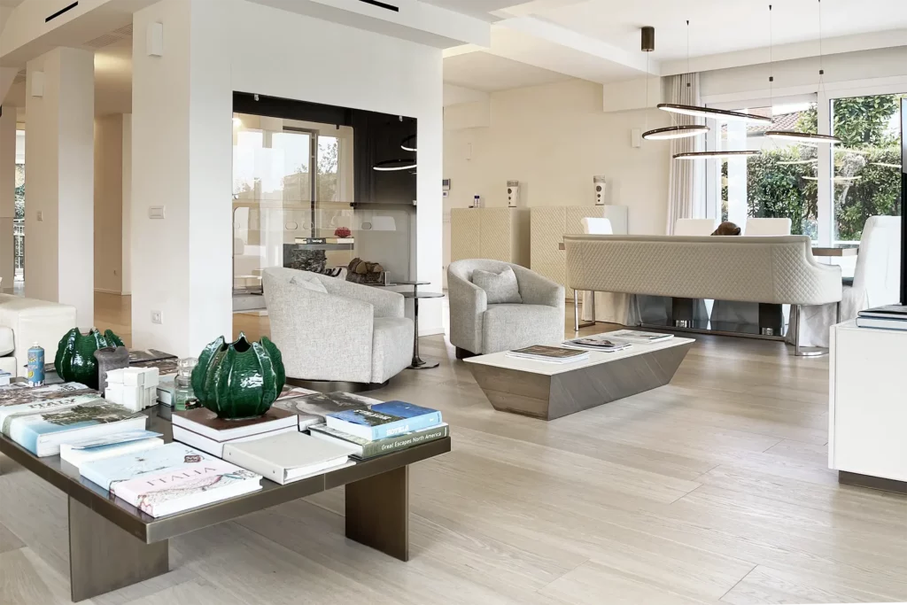 Immobiliare, immagine salotto moderno con tavolo da fumo, libri, camino, poltrone, sala pranzo, illuminazione moderna. Immagine realizzata dal fotografo immobiliare duzimage La Spezia per agenzia TheDreamRe Forte dei Marmi