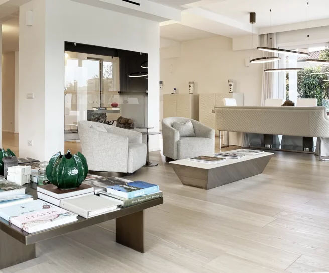 Immobiliare, immagine salotto moderno con tavolo da fumo, libri, camino, poltrone, sala pranzo, illuminazione moderna. Immagine realizzata dal fotografo immobiliare duzimage La Spezia per agenzia TheDreamRe Forte dei Marmi